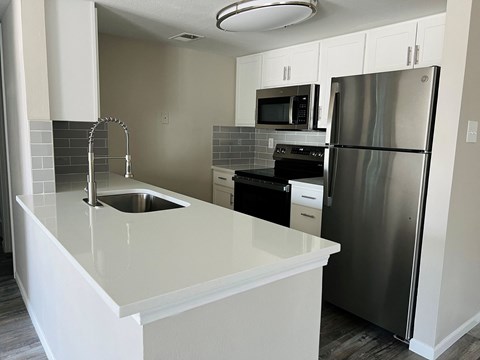 A kitchen with a white counter top and stainless steel appliances.
