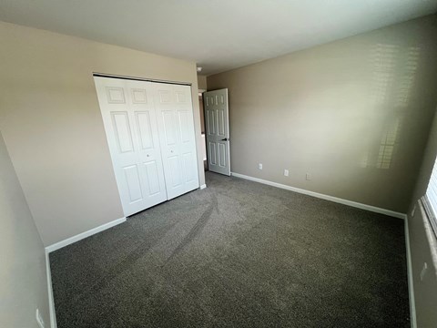 A room with a white door and a grey carpet.