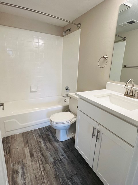 A white toilet sits in a bathroom next to a sink.