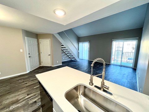 A kitchen with a sink and a staircase in the background.