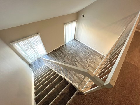 A staircase with a metal railing and wooden steps leading to a room with a window.