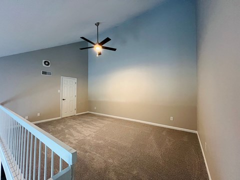 A room with a ceiling fan and a carpeted floor.