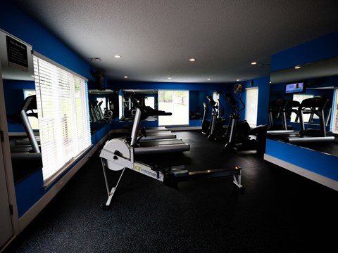 a gym with various machines and windows in a large room