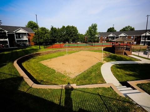 a baseball field in a park with houses in the background
