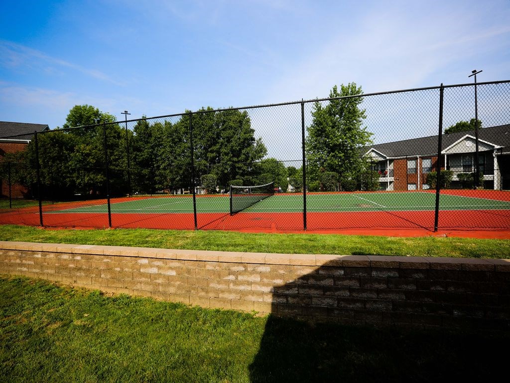 a tennis court with a fence in front of a house