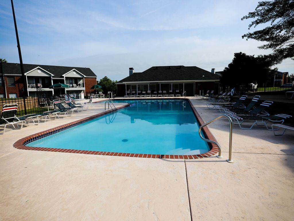 a swimming pool with chairs around it in front of a building
