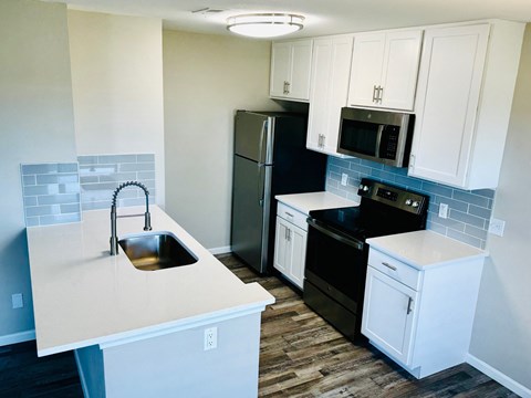 A kitchen with black appliances and white cabinets.
