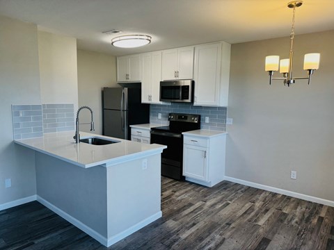 A kitchen with a sink, refrigerator, and microwave.