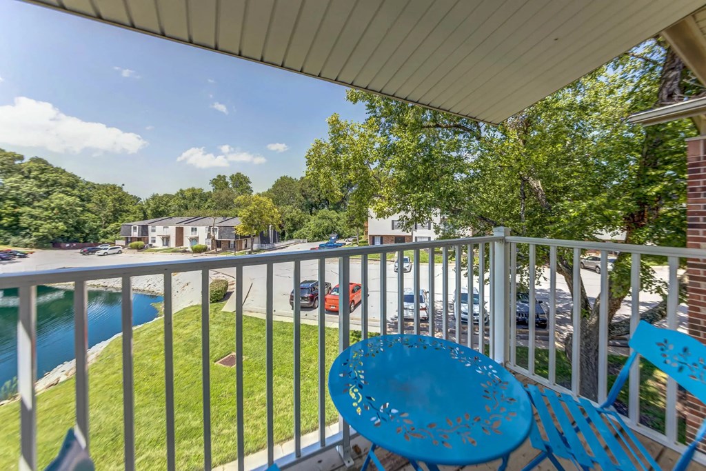 a patio with blue chairs and a table on a balcony