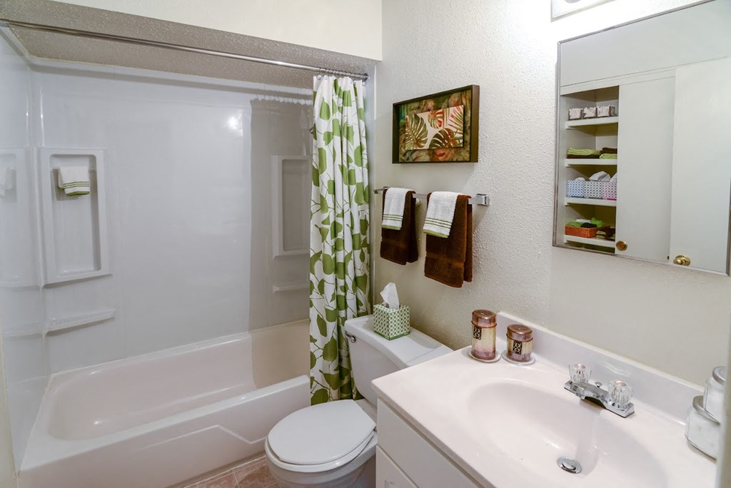 a white bathroom with a green and white shower curtain