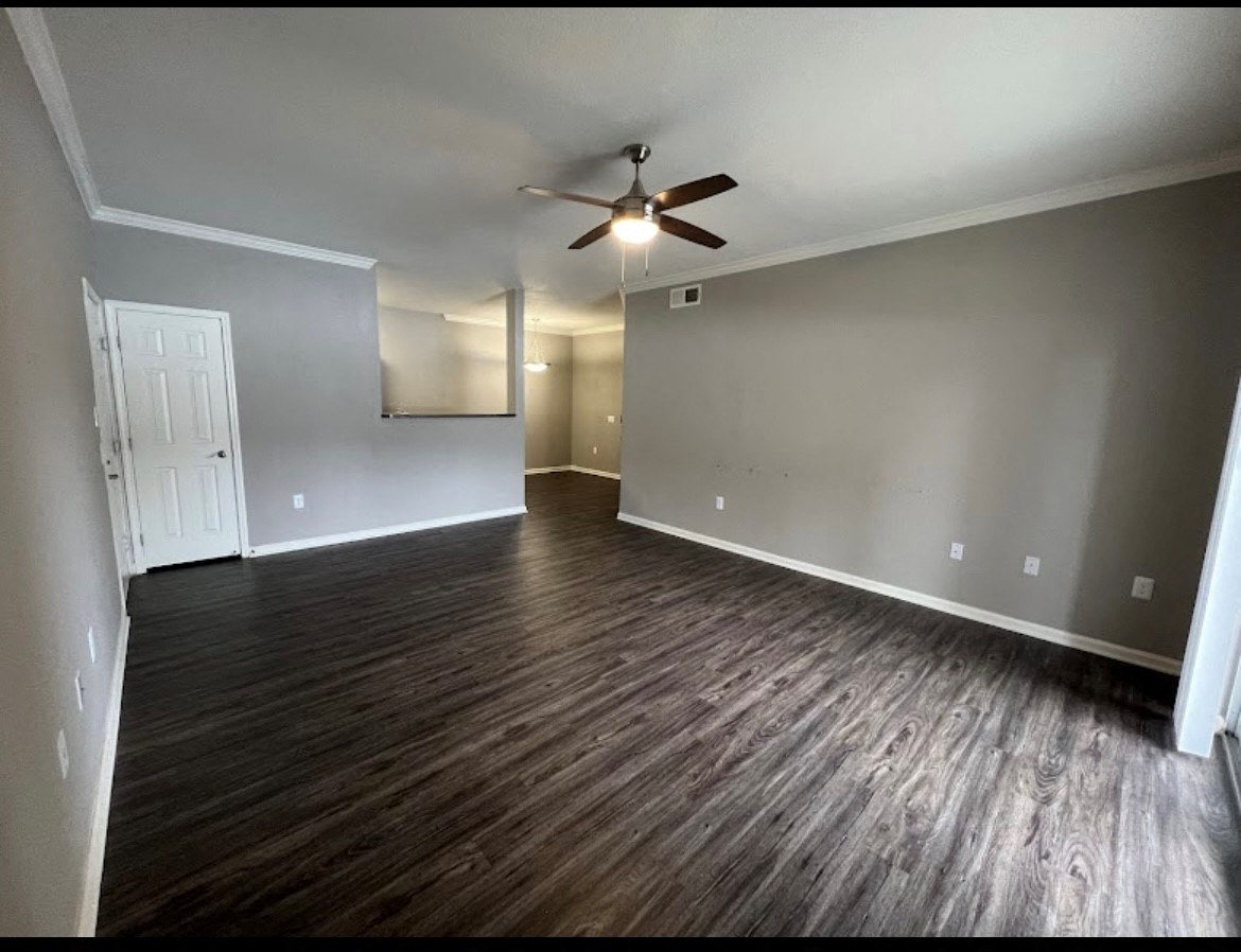 an empty living room with wood floors and a ceiling fan