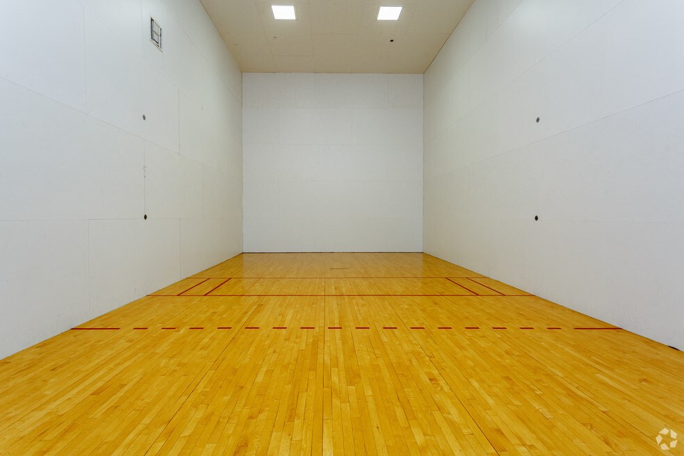 a large white room with a wooden floor and a racquetball court