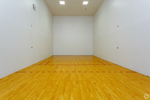 a large white room with a wooden floor and a racquetball court