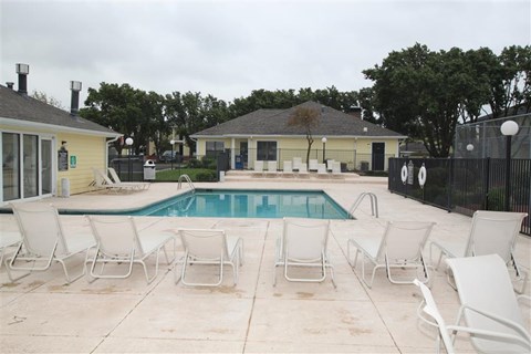 a swimming pool with white chairs around it