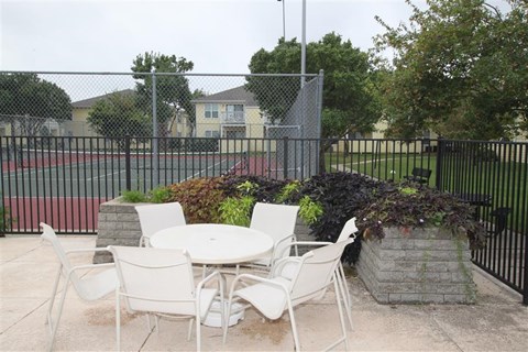 a patio with a table and chairs in front of a fence