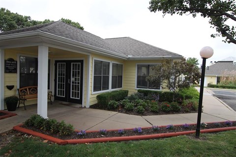 a front porch of a yellow house with a driveway