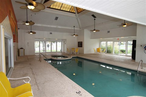 a swimming pool in a room with yellow chairs