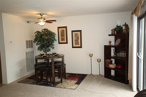 a living room with a table and a ceiling fan