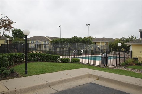 a yard with a swimming pool and a wrought iron fence