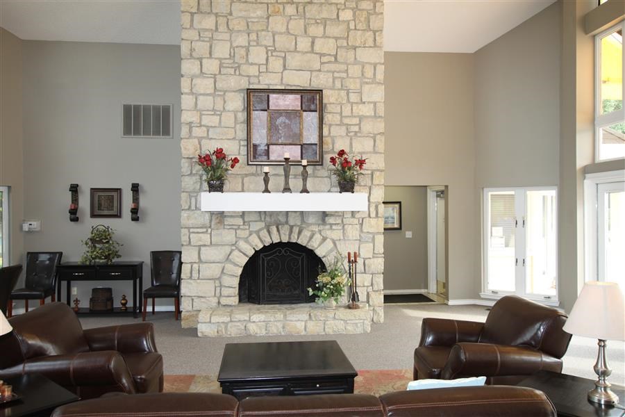 a living room with a stone fireplace and leather furniture