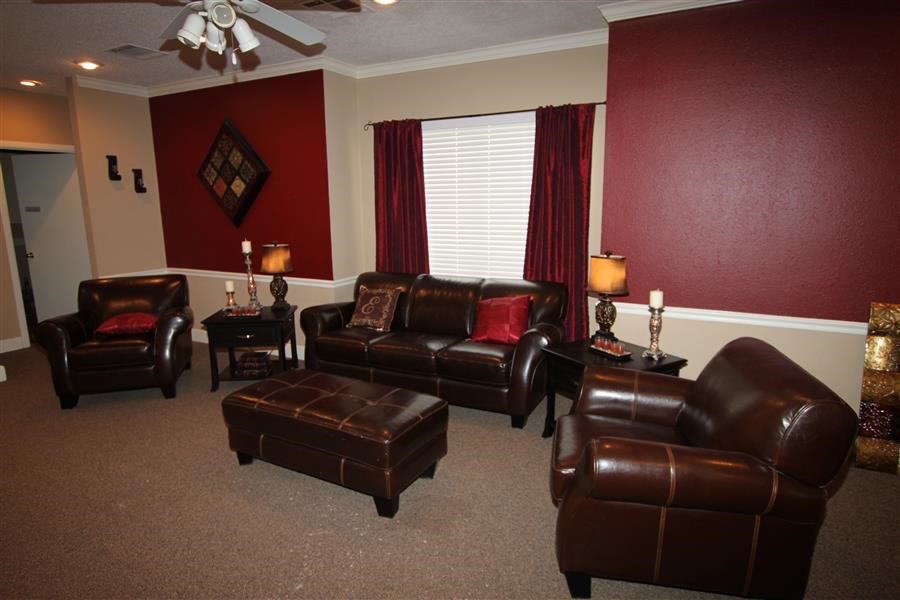 a living room with leather furniture and a red wall