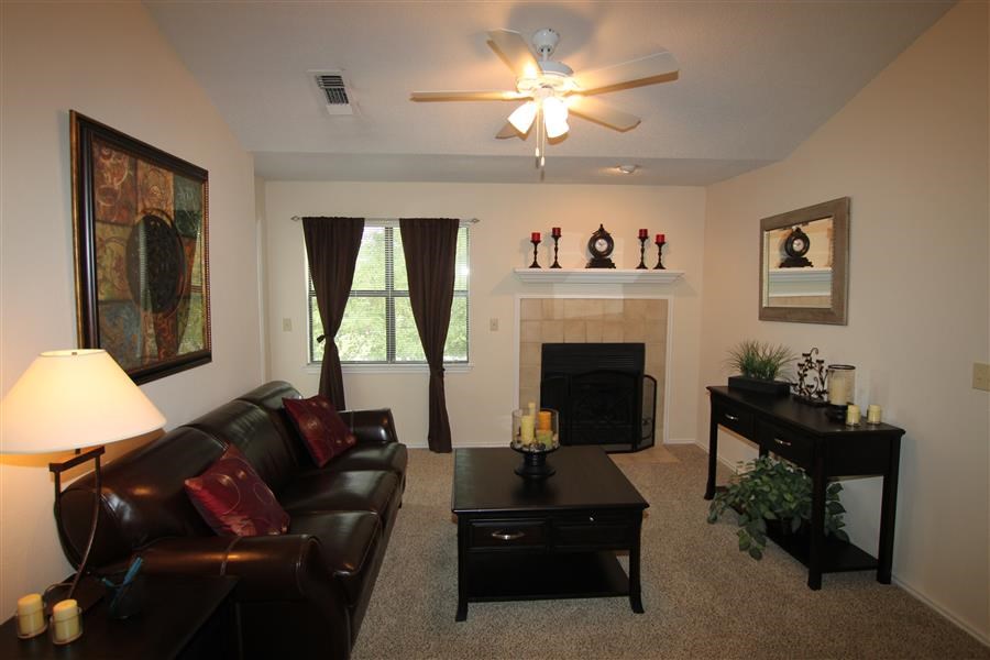 a living room with a leather couch and a ceiling fan