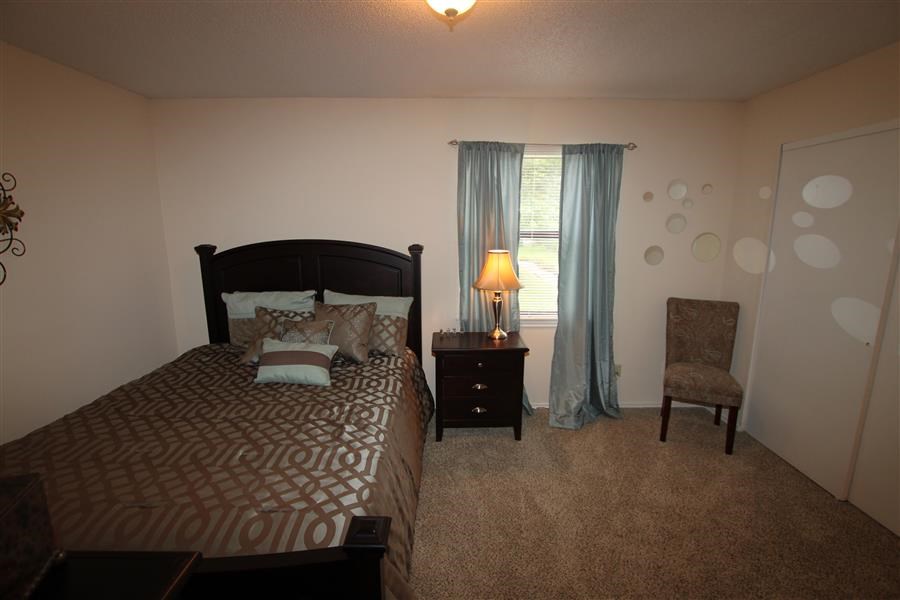 a bedroom with a bed and a chair and a lamp