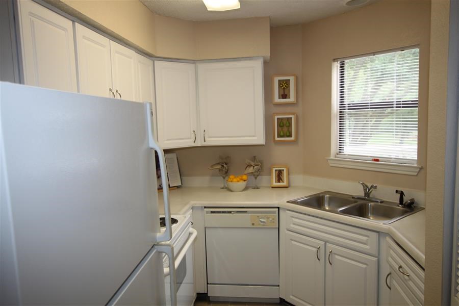 a white kitchen with a refrigerator and a sink