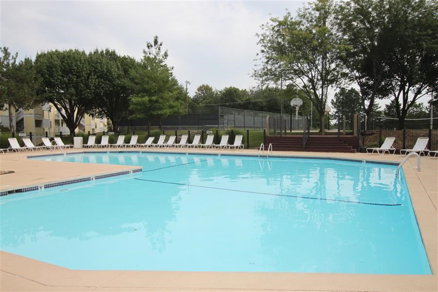 a large swimming pool with white chairs around it