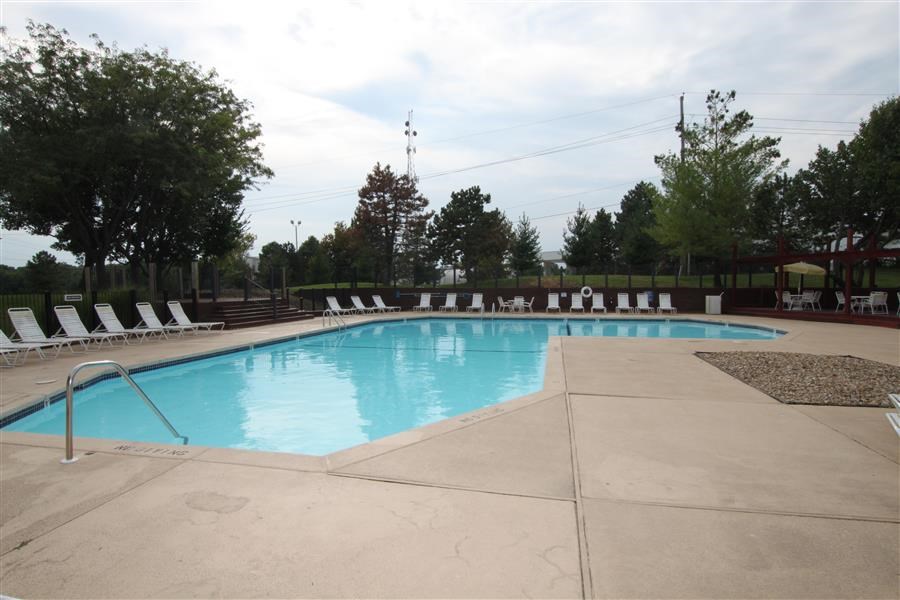 a swimming pool with white chairs around it