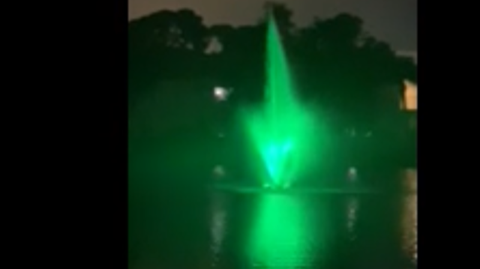 a green water fountain is lit up at night