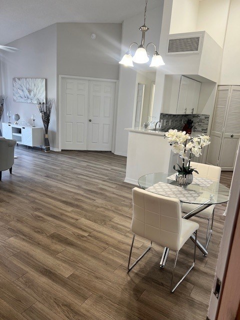 A white chair is in front of a glass table with a vase of white flowers on it.