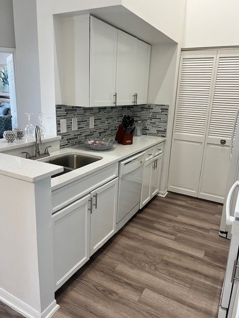 A kitchen with white cabinets and a wooden floor.