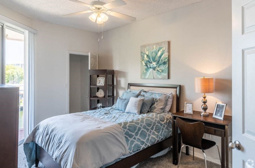 a bedroom with a bed and a desk with a window