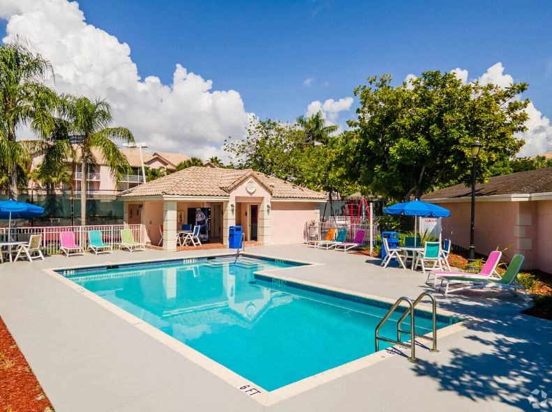 a swimming pool with chairs around it and a house