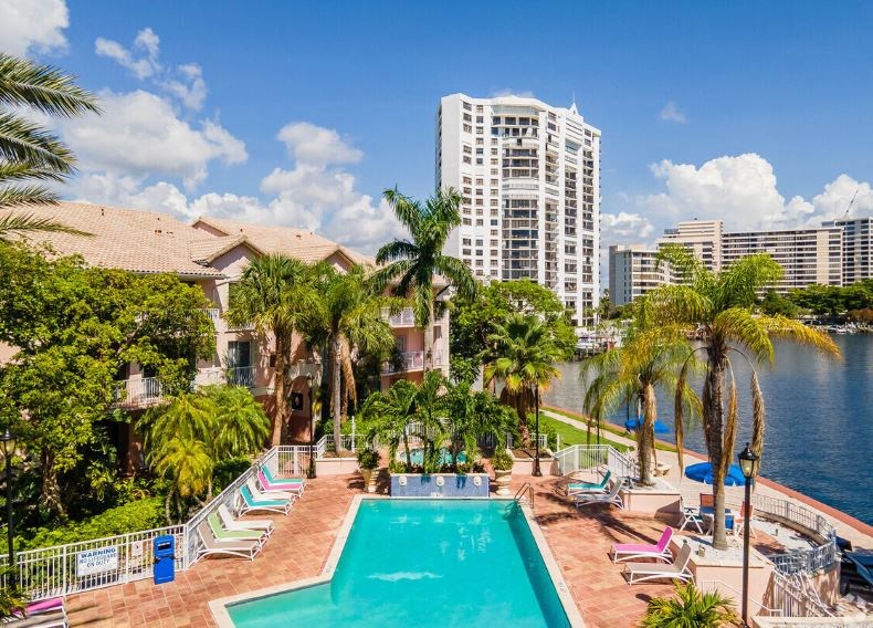 a large swimming pool with palm trees and a building in the background