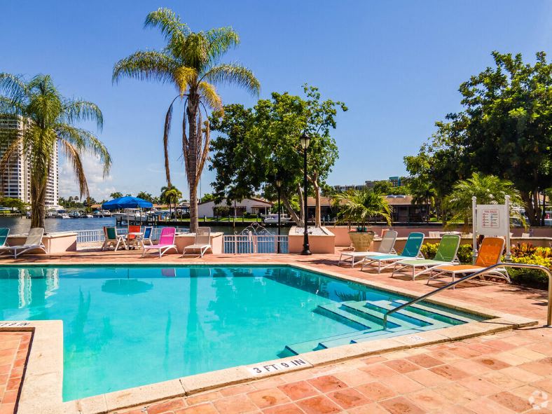 a swimming pool with chairs and palm trees