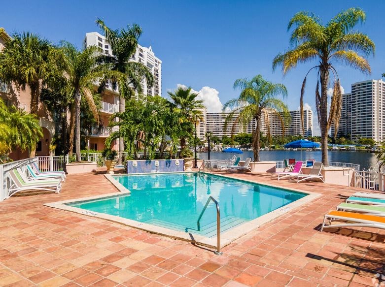 a swimming pool with palm trees and buildings in the background