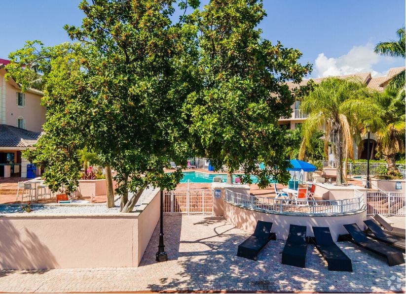 a swimming pool with picnic tables and trees