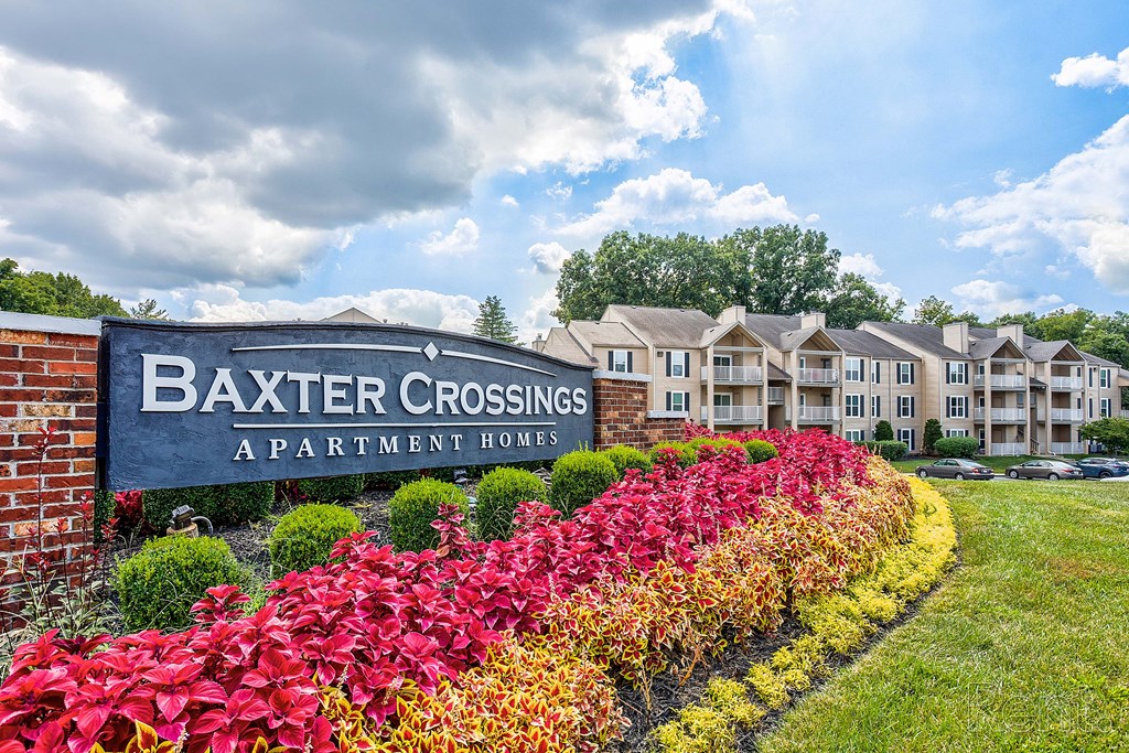 a sign for baker crossing apartments with a flower garden in front of the building