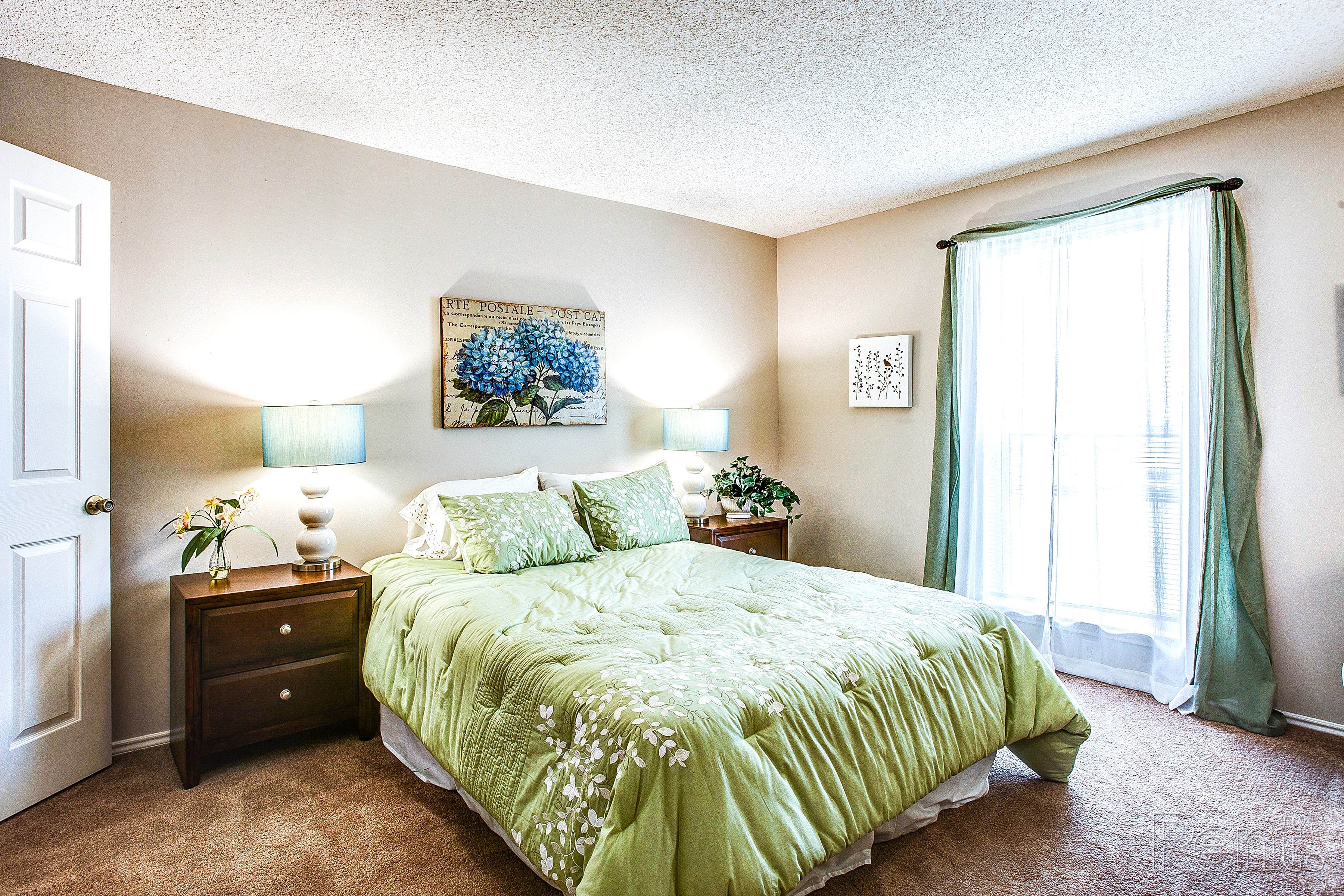 a bedroom with a green bed and a window