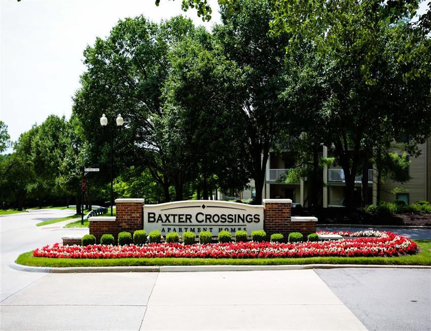 a sign for battery crossings in front of a garden of flowers
