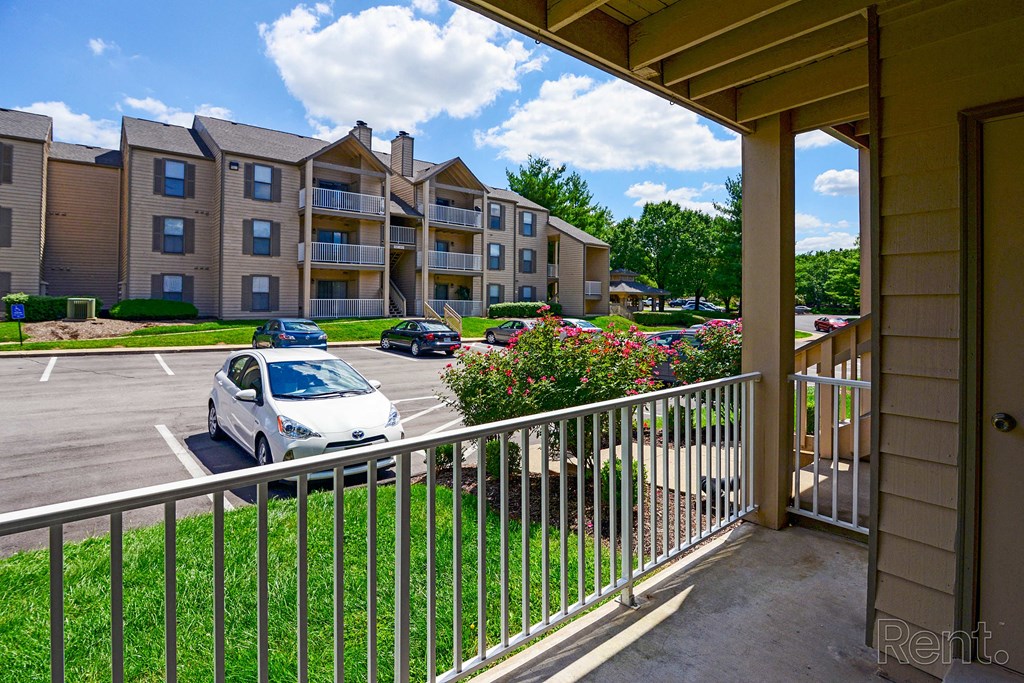 the view from the balcony of an apartment building with cars parked in a parking lot
