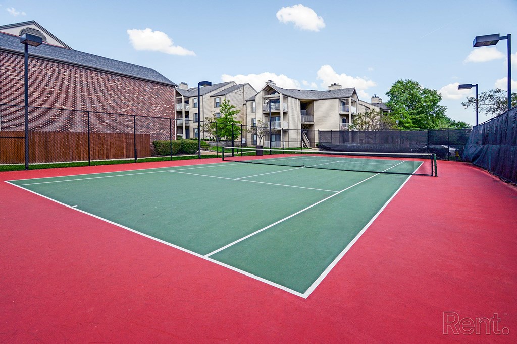 a tennis court with apartments in the background