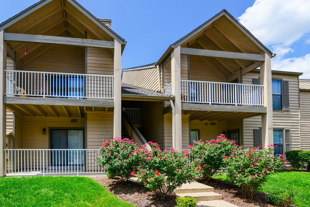 a house with two balconies and a yard with flowers