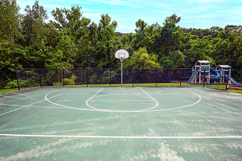 a basketball court with a playground in the background