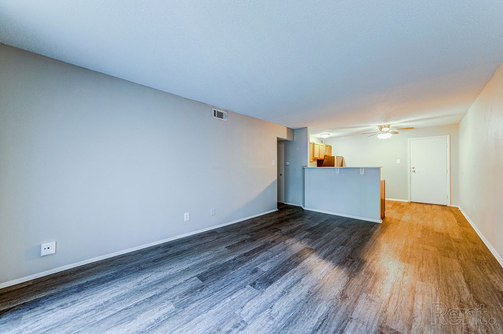 the living room and kitchen of an apartment with wood flooring