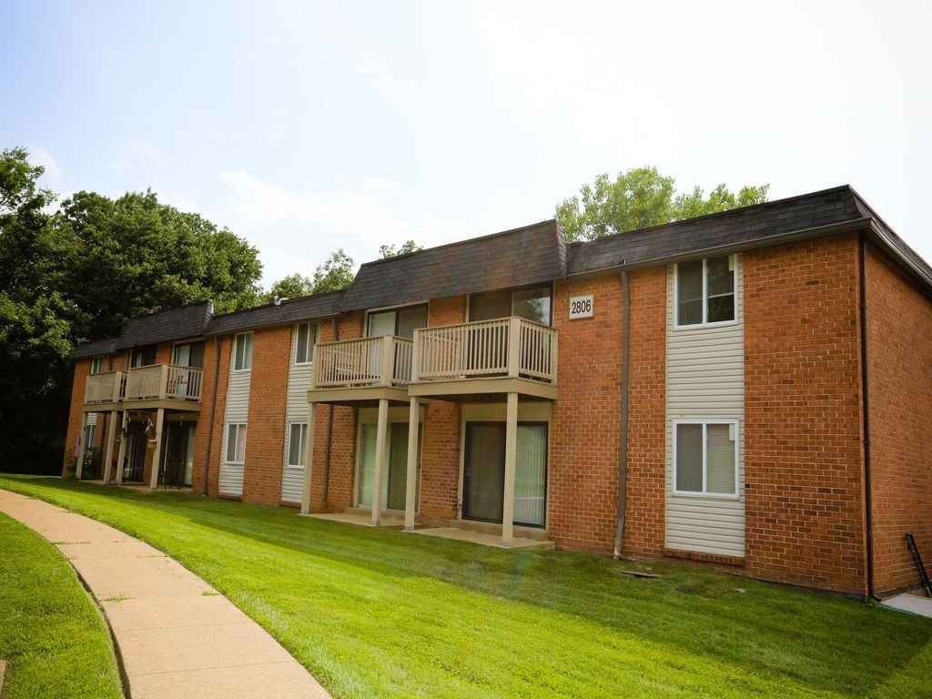 an apartment building with a green lawn and a sidewalk