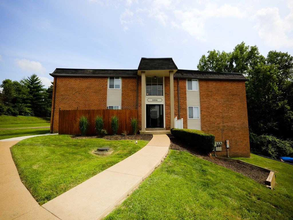 the front of a brick building with a sidewalk and grass
