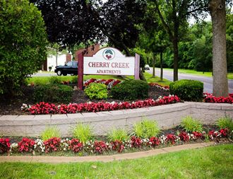 a flower garden in front of a cherry creek apartments sign